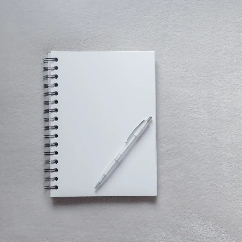 A spiral notebook and pen on a grey surface