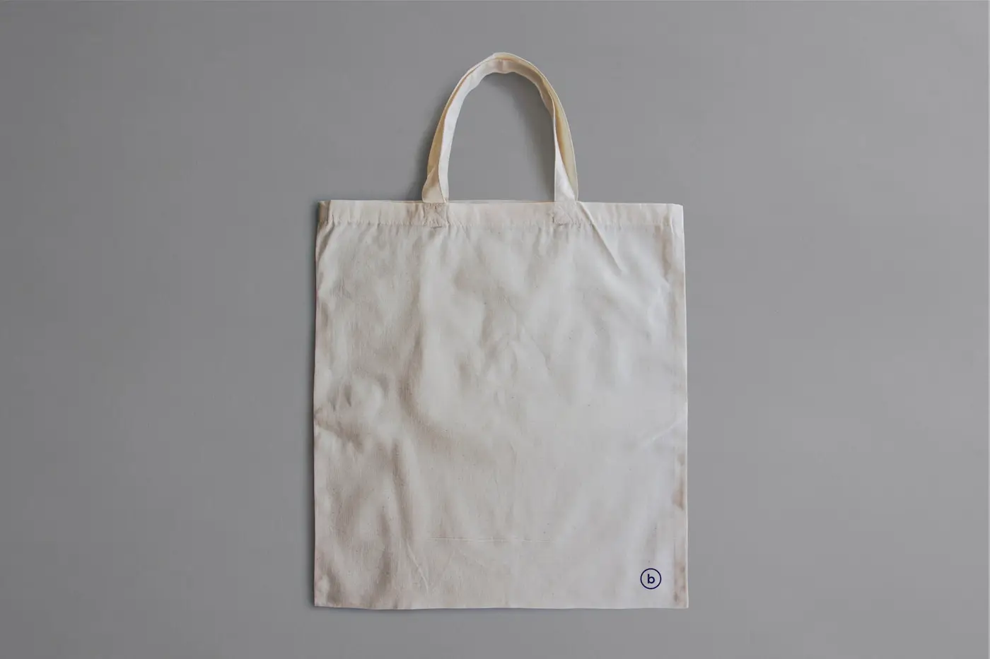 A plain canvas tote bag on a grey background